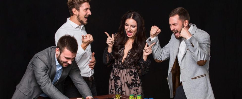 group-young-people-roulette-table-black-background-young-man-rejoices-victory